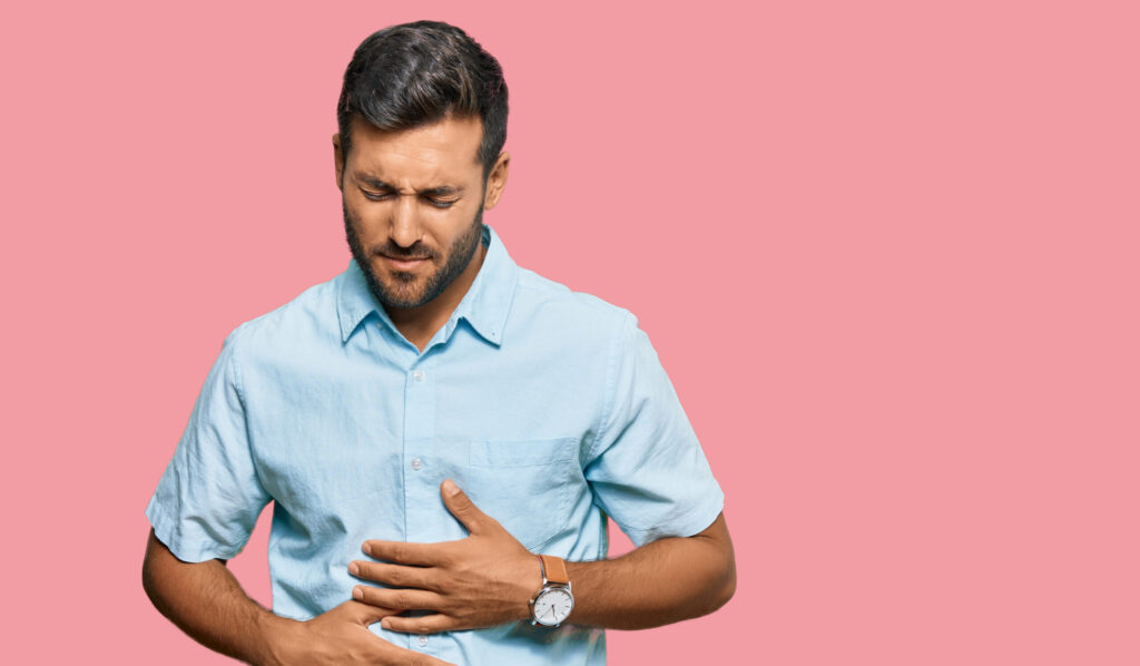 Handsome hispanic man wearing casual clothes with hand on stomach because indigestion, painful illness feeling unwell. ache concept.