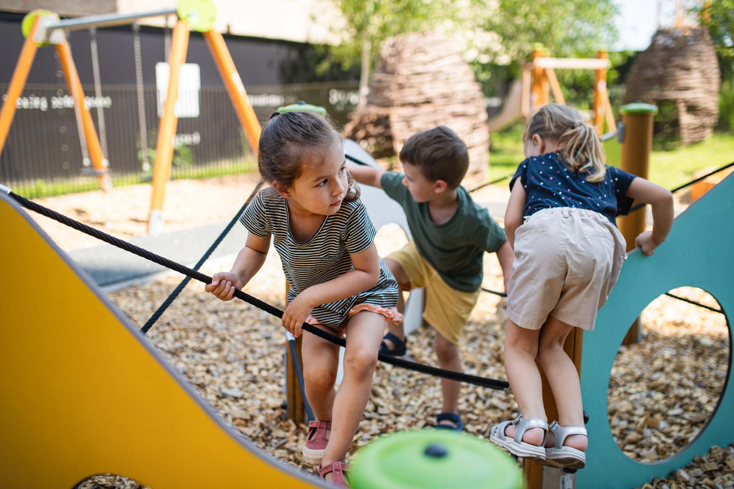 Group of small nursery school children playing outdoors on playground.